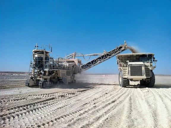 Surface-mining machine excavating rock alongside a haul truck